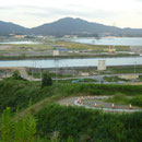 ３８５　送出口付近から見た陸前高田（２）河川両岸にベルトコンベアの橋脚跡、向こ う岸に一本松とユースホステル