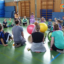 Kinder sitzen im Kreis gegenüber, nehmen Kontakt auf und spielen sich den Ball zu