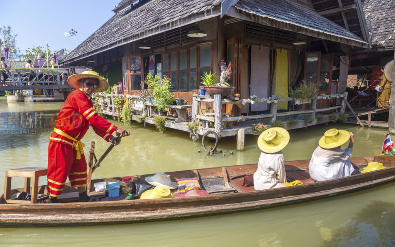 Ein thailändischer Mann fährt auf einem Longtailboot zwei Touristen umher