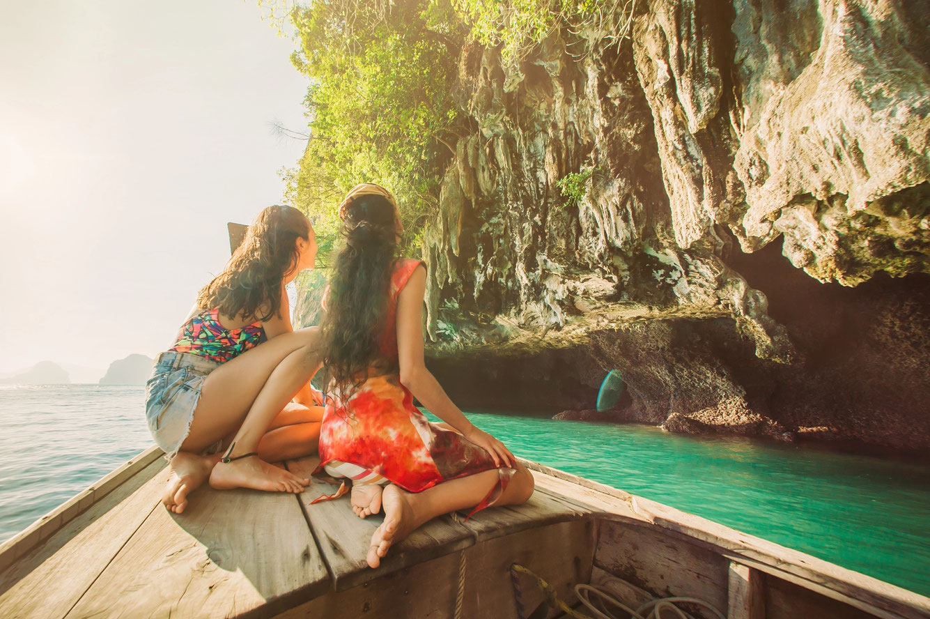 Kurzfristiger Thailand Urlaub - zwei Touristinnen fahren auf einem Longtailboat in Krabi
