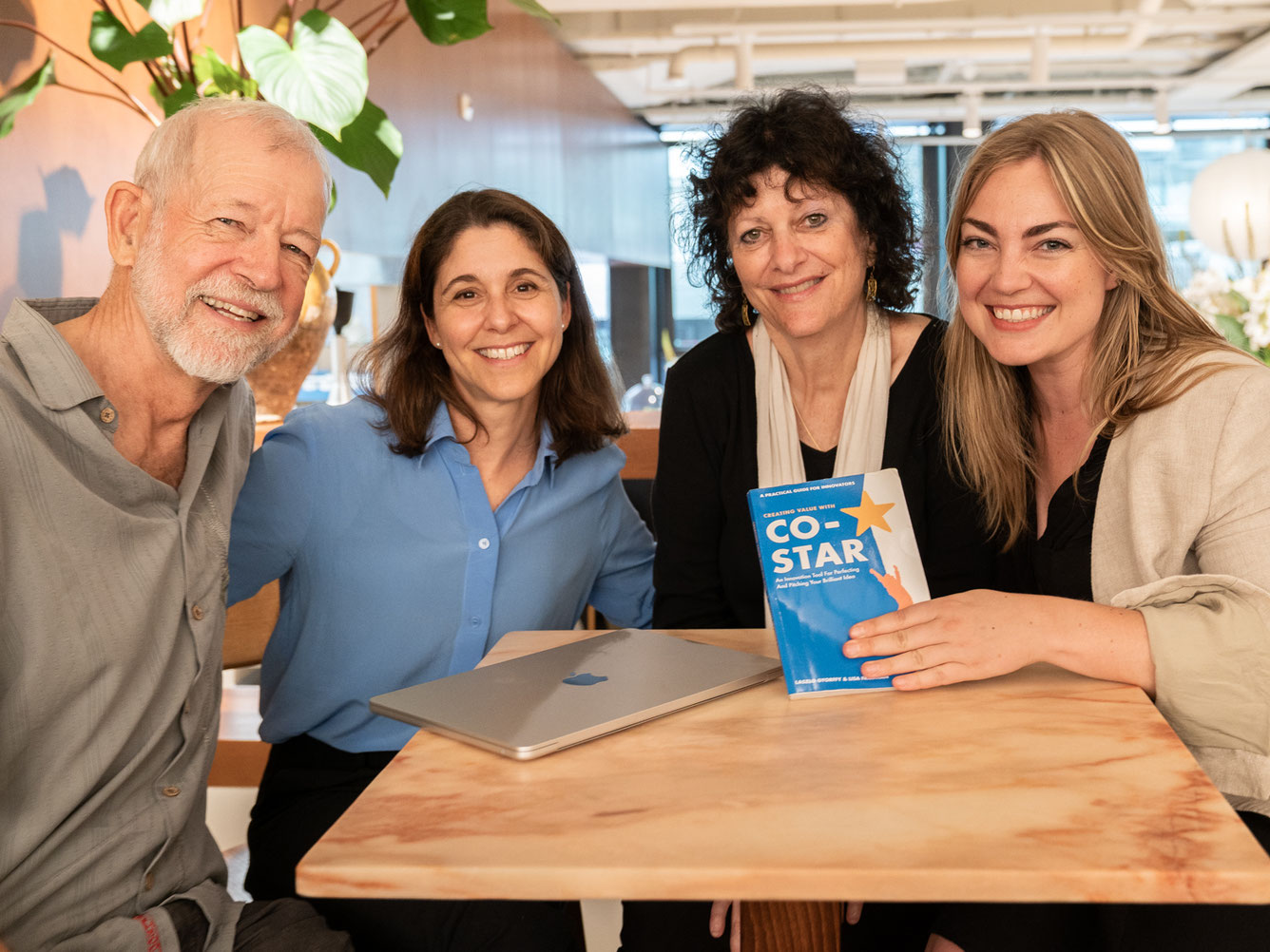 Vier_Personen_an_Tisch_mit_Buch_CO-STAR_von_links_nach_rechts_HermanGyr_SimoneRies_LisaFriedmann_JessicaThompson