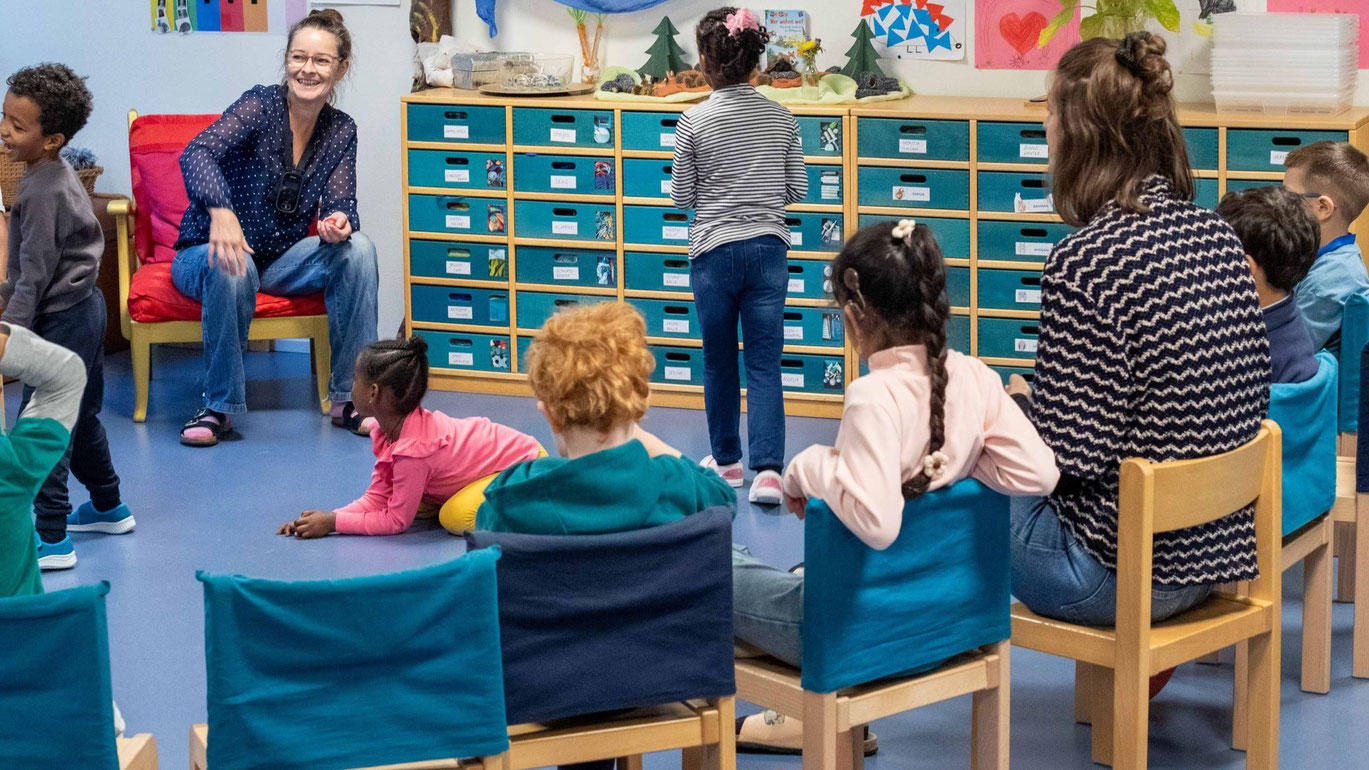 Sitzkreis_Basisstufe_verschiedene_Kinder_zwei_Lehrerinnen_sitzen_im_Kreis_im_Schulzimmer