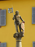Sehenswürdigkeiten Staufen im Breisgau: Kleine Steinfigur auf dem Brunnen vor dem Rathaus.