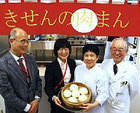 肉まんを手に「心を込めて作っています」と語る大川さん(右から2人目)
