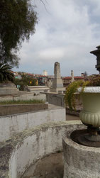 Un pot de fleur en béton et des monuments funéraires en béton du cimetière de Valparaiso avec une vue sur une partie de la colline d'en face