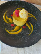 Un dessert très original dans une assiette noire faisant resortir ses couleurs et ses formes faisant pensée au soleil