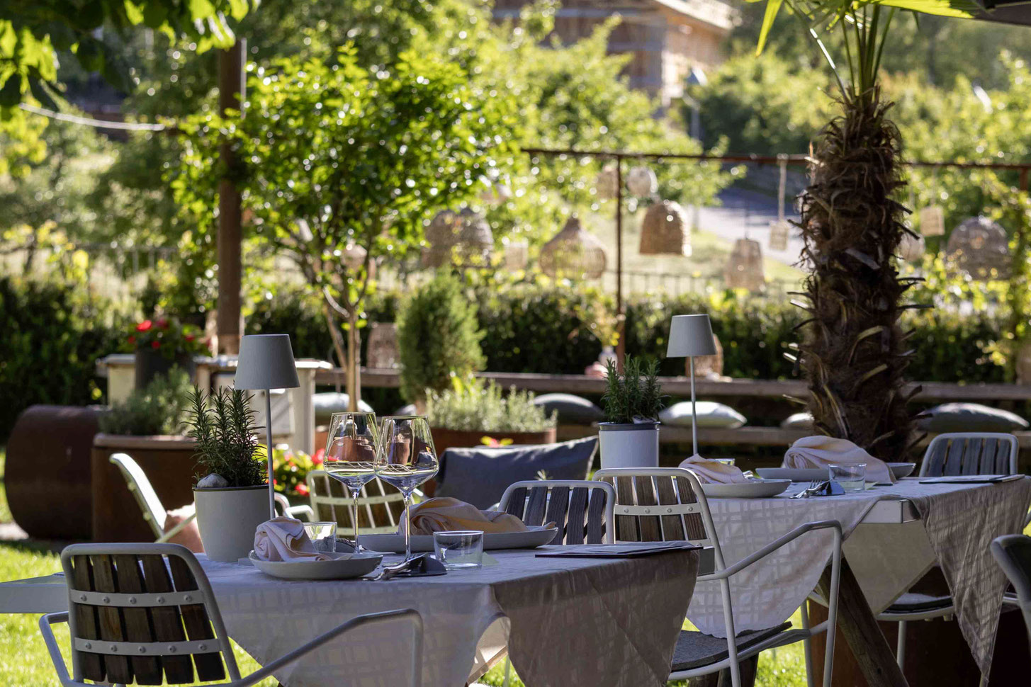 A lovingly decorated garden terrace with views of the countryside at the PETRUS boutique hotel in Reischach-Bruneck • South Tyrol, inviting guests to enjoy a relaxing breakfast or dinner in a natural setting.