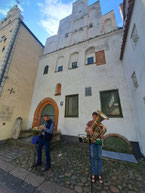 two musicians playing tuba and trumpet in front of Three Brothers medieval houses in Old Riga