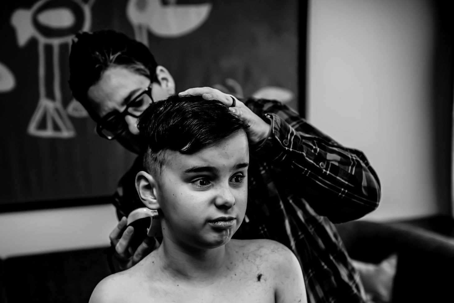 Black and white photo of mom giving child a haircut. 