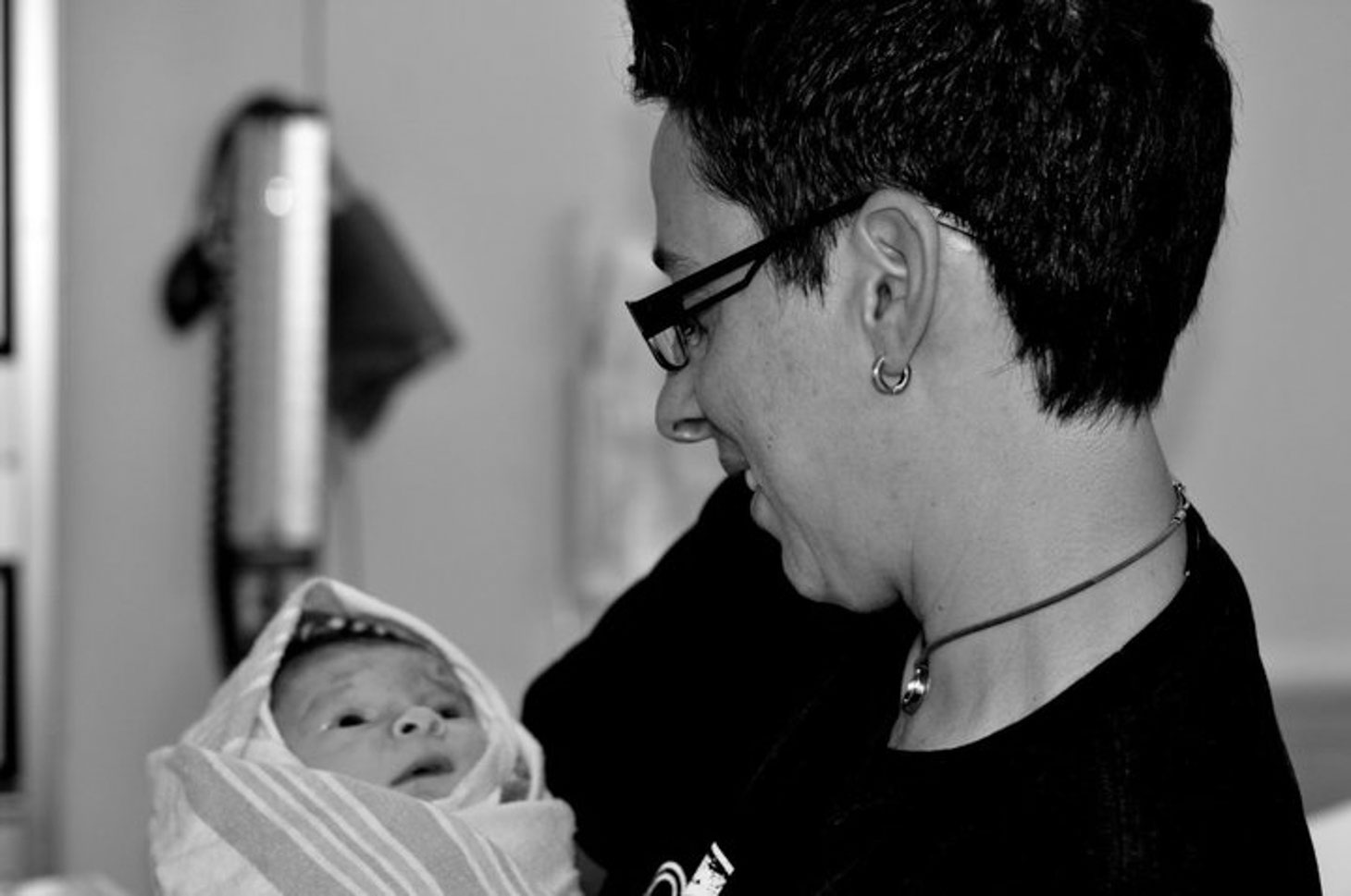 Black and white photo of a new mom holding her baby wrapped in a blanket. 