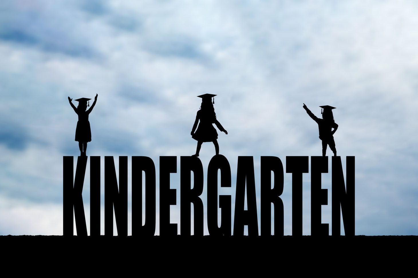 silhouettes of 3 girls with grad caps in front of a blue sky on top of the letters KINDERGARTEN