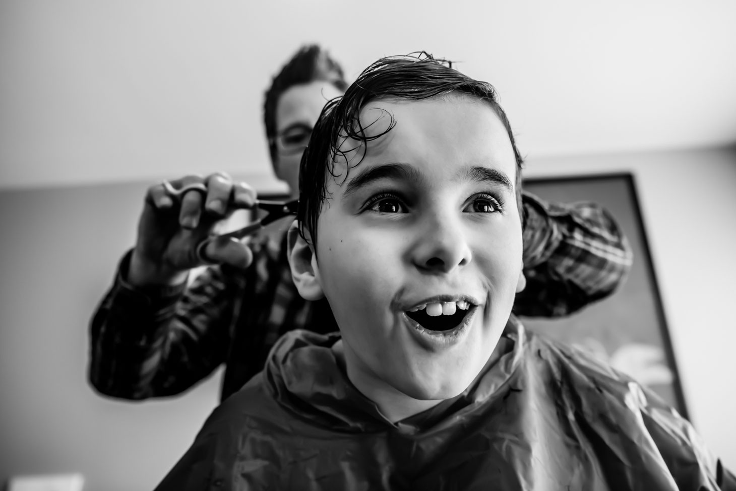 Black and white photo of mom giving child a haircut. 