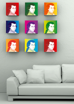 Nine identical but differently colored cartoon portraits of Mozart hang above a gray sofa in the lower half of the picture in front of a gray wall.