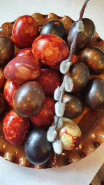 Red, gold and purple painted Latvian Easter eggs with a twig of a willow branch in the middle