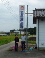 写真は、蔵の看板前で撮った岩倉夫妻です。廻りは畑だらけです。いつも二人三脚。