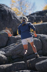 Man climbing up over large boulders.