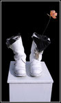 Materialmontage “Einzig mögliche Verwendung” Werkverzeichnis 1.017 / ca. 1996, Soldatenstiefel mit weißer Farbe besprüht, mit schwarzem Tuch, weißen Kerzen und Blumen befüllt