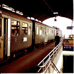 Ein Zug auf Gleis 10 im Bahnhof Basel SBB wartet auf das Abfahrtssignal des rot bekappten Bahnhofsvorstandes, 1980