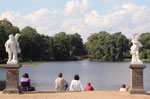 Sommer-Sonne im Schlosspark. Menschen sitzen auf den Stufen zum See mit Blick auf die Rote Brücke. Foto: Helga Karl