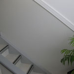 Treppenhausgestaltung mit Laminatverlegung im Boden- und Stufenbereich, Glasgewebe an den Wandflächen und dekorativen Zierprofilen.