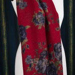 Étole en laine rouge intense portant des motifs floraux bleu marine et vert kaki.