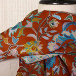 Étole orange en laine et soie, sur laquelle sont imprimés des fleurs multicolores.
