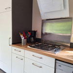 Plan de travail bois avec plaque gaz inox, hotte design blanche et lave-vaisselle intégré, cuisine du Bois Jaune