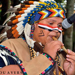 Hugo Jr. playing traditional music with feather headdress in Foz do Iguacu
