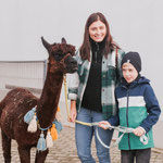 Mutter und Kind zusammen mit Alpaka auf dem Pointnerhof