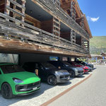 7 gleiche Porsches in diversen Farben stehen vor einem Hoteleingang