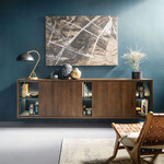 Modernes Sideboard in dunkler Holzoptik mit Glaseinsätzen und stilvollen Accessoires, elegantes Wohnzimmermöbel vor blauer Wand.