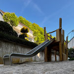 Rutschenturm ohne Dach auf Kinderspielplatz mit Sandaufzug und Motorikelementen zum klettern und rutschen.
