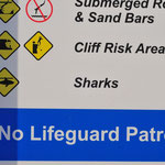 Hier wird vor Haien gewarnt. Es fliegt auch regelmäßig ein Hubschrauber die Küstenlinie ab, um nach Haien Ausschau zu halten.