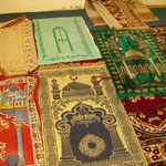 Religious rugs in a small building next to the road.