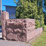 Jäteastiakin graniittimuurin suojassa. Muurin oikealla puolella oleva viherkaistale kuuluu kiinteistöön.