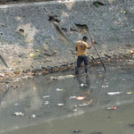 Ein Arbeiter fischt nach Müll, damit nichts verstopft.
