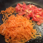 Karotte und Tomanten in Butter anschwitzen und ebenfalls in die Bouillon geben