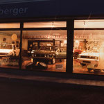 Ansicht des beleuchteten Ausstellungsraum mit 3 Fahrzeugen und Reifen bzw. Felgen, Bild aus dem Jahr 1985 
