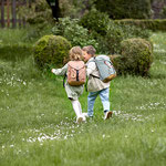 2 Kinder laufen über Wiese mit Mini Outdoor Rucksäcken von LÄSSIG