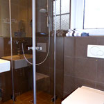 Badezimmer mit vollverglaster Eckdusche und Fön