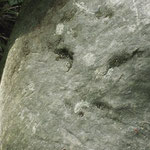Skizzenhaft angedeutete Gesichtszüge in einem Steinbrocken.