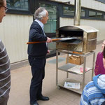 Direktor Blaum backt in einem Steinbackofen auf dem Schulhof Fladenbrot und Brötchen