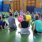 Kinder sitzen im Kreis gegenüber, nehmen Kontakt auf und spielen sich den Ball zu