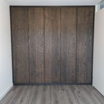 Door stefig op maat gemaakte inbouwkast met eiken fineer deuren afgewerkt met Rubio monocoat charcoal olie. Gemonteerd in Hoogvliet.