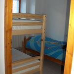 chambre avec deux lits superposés et un lit simple