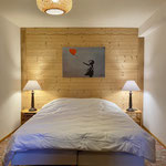Chambre cosy avec lit double, lampes de chevet et mur en bois dans un chalet de montagne aux Arcs 1600
