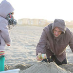 強風の中、友人のクリストフと一緒に「砂のケーキ」を作る娘。