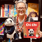 Woman in panda ears holding a fluffy panda and a book