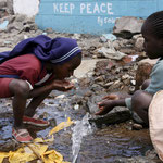 Bambini di Kibera bevono in un canale di scolo.