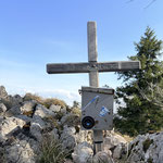 Auf diesem steht ein schlichtes kleines Holzkreuz mit Buchkassette